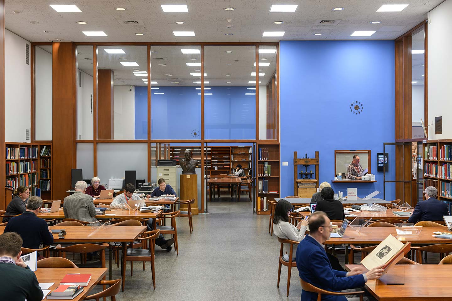 Various long wooden tables stand in a room lined with wooden bookshelves